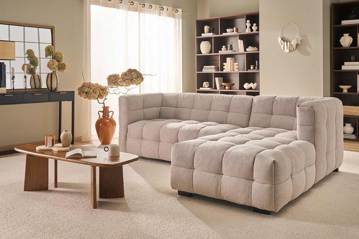 Canap� d'angle droit 3 places beige en tissu effet velours, dans un salon avec table basse.