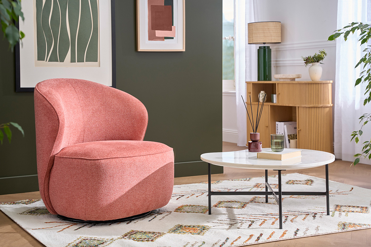 Fauteuil design terracotta pivotant en tissu effet velours vu de 3/4, dans un salon avec table basse.
