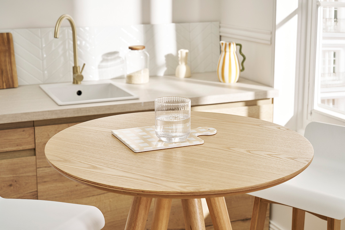 Table de bar ronde scandinave en bois, vue de pr�s avec un verre d'eau.