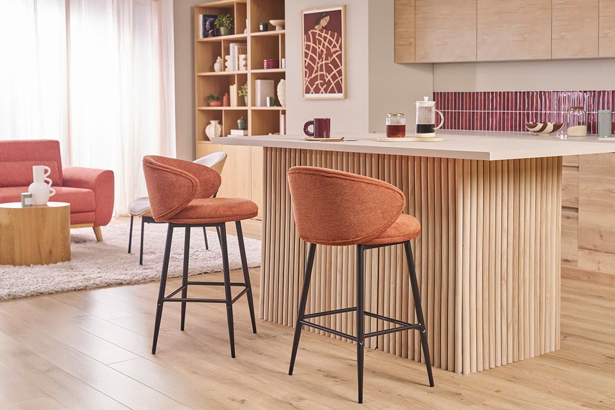 Tabourets de bar en tissu terre br�l�e et m�tal noir devant un �lot central en bois.
